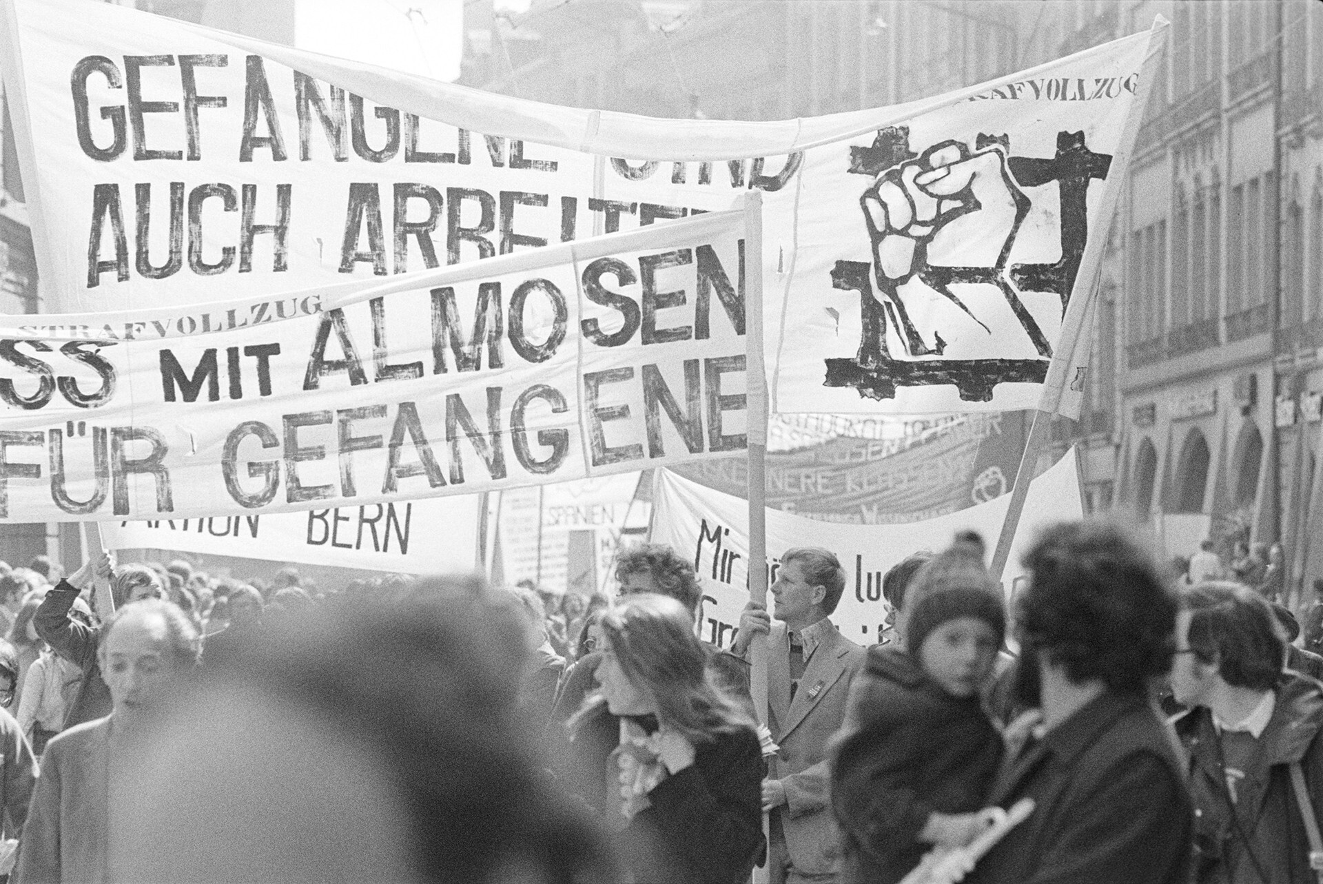 Black-and-white photograph of the May Day demonstration in Bern in 1976. Several protesters with banners protesting against the penal system.