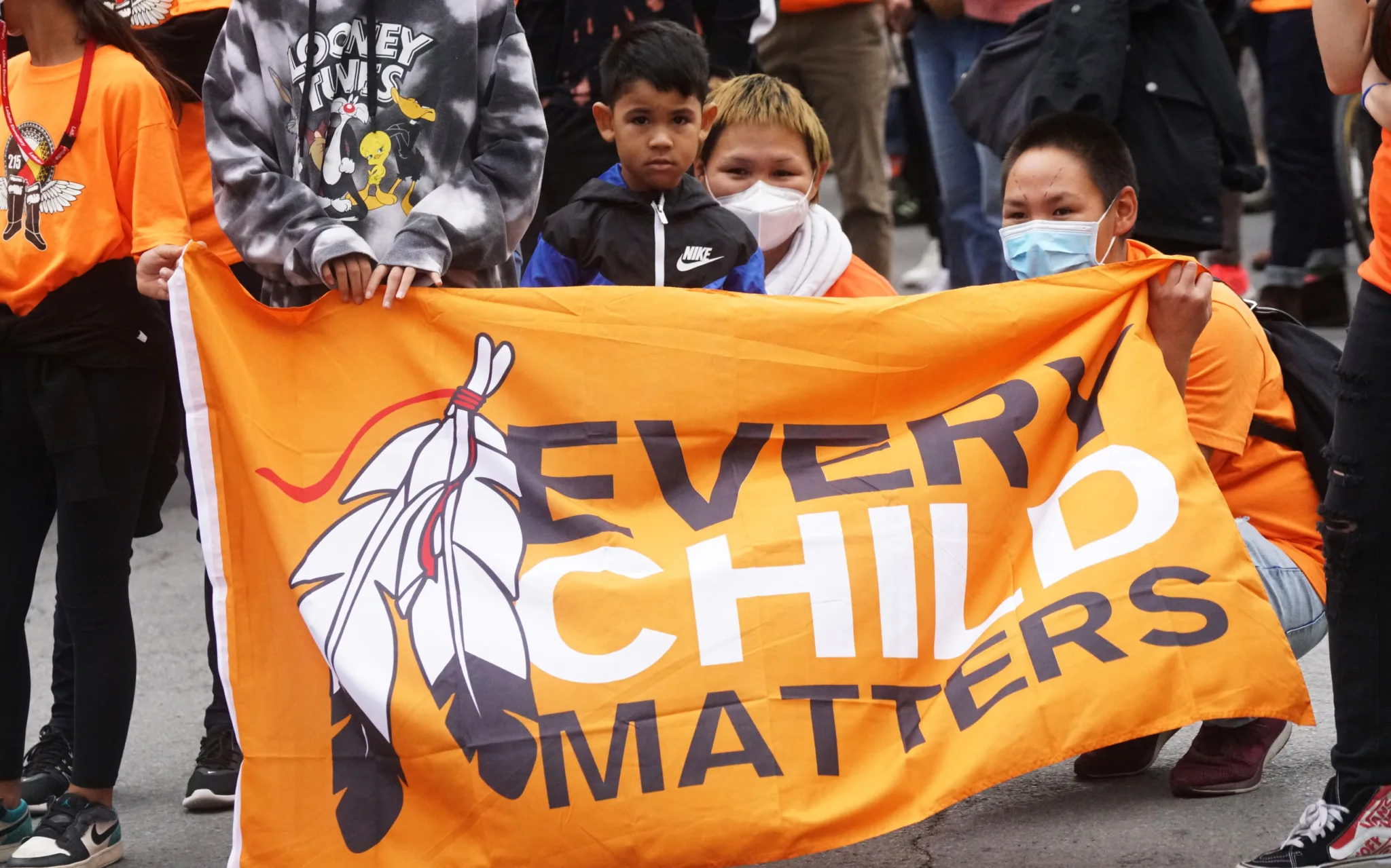 Colour photograph of several children and two adults behind a banner reading ‘Every Child Matters’. ‘Every Child Matters’ is a movement in Canada that focuses on the rights, well-being and dignity of all children, especially indigenous children.